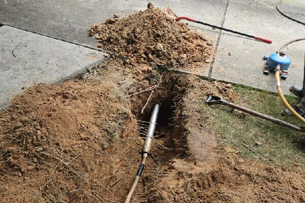 Exposed water pipe with a repair connection in a yard excavation